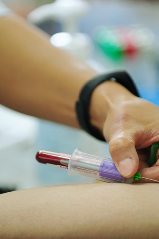 Healthcare professional drawing blood from the arm of a patient